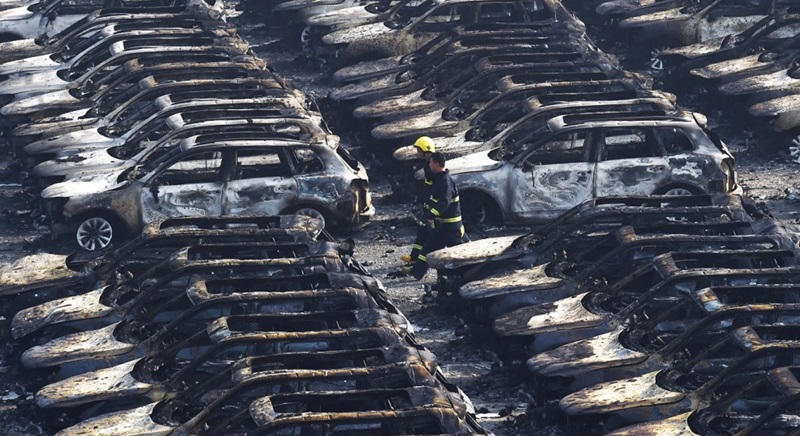 Firefighters walk past rows of charred cars near the site of the explosions in Tianjin