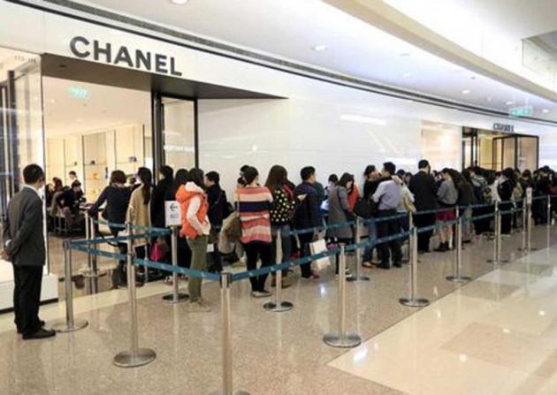 Customers line up as they wait to go inside a Chanel shop at a shopping mall