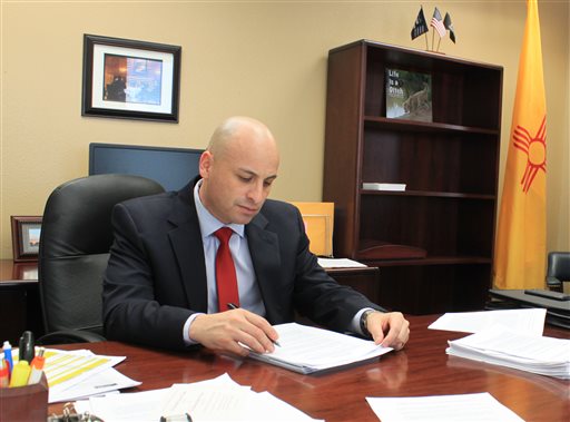 New Mexico Attorney General Hector Balderas reviews documents related to a lawsuit against one of the nation's largest nursing home chains in his office in Albuquerque N.M. on Tuesday