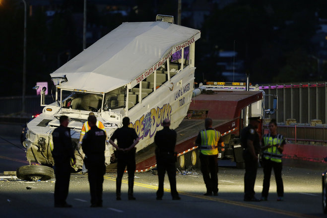 Police officers and other officials watch as a'Ride the Ducks tourist vehicle is loaded onto a flatbed tow truck in the late evening Thursday Sept. 24 2015 after it was involved in a fatal crash with a charter passenger bus earlier in the day in Seat