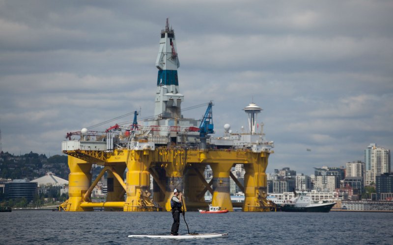 A man on a stand up paddle board is seen in front of the Shell Oil Company's drilling rig Polar Pioneer along the Puget Sound in Seattle Washington