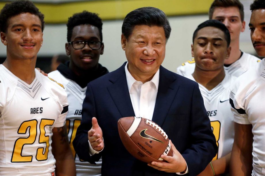 Chinese President Xi Jinping poses with football players and a football he was given during a visit to Lincoln High School Wednesday Sept. 23 2015 in Tacoma Wash. Xi is on the second of a three-day trip to Seattle before traveling to Washington D.C