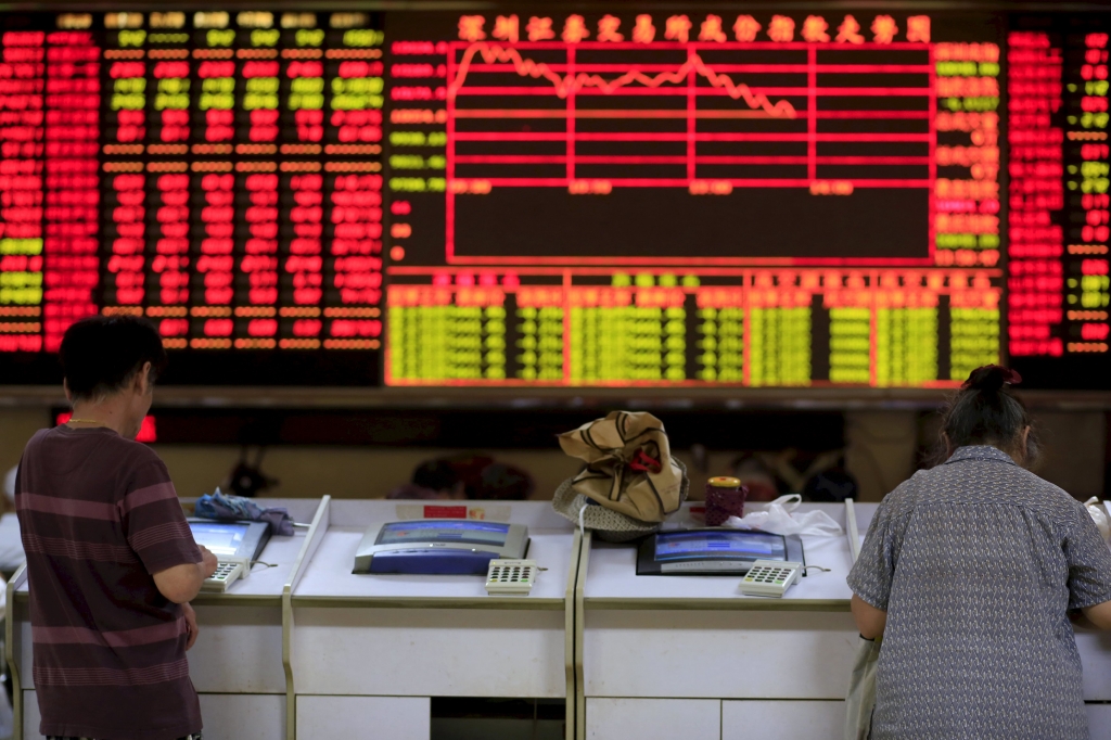 Investors look at computer screens in front of an electronic board showing stock information at a brokerage house in Shanghai China in this file