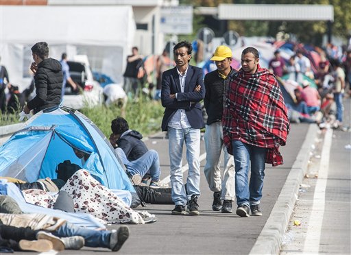 Refugees walk past others resting on the ground at the border station between Serbia and Hungary near Horgos Serbia Wednesday Sept. 16 2015. Small groups of migrants continued to sneak into Hungary on Wednesday a day after the country sealed its bord