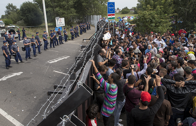 Migrants stand in front of a barrier at the border with Hungary near the village of Horgos Serbia