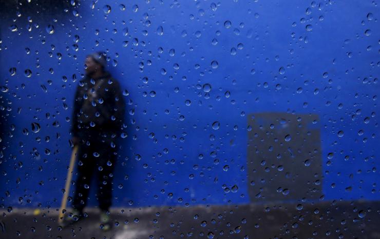 A job seeker is seen through a car window as he waits for casual work as a builder outside a hardware store in Cape Town