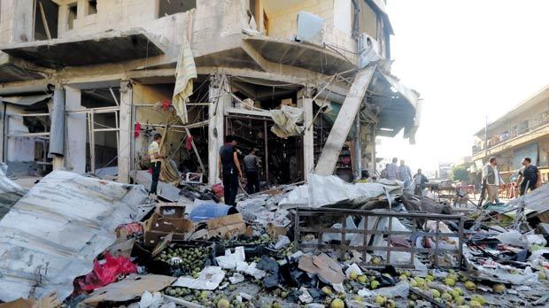 Residents gather at a site damaged by what activists said was an air strike from President Bashar al-Assad’s forces at a vegetable market in Idlib. Yesterday Syrian troops moved out of the area