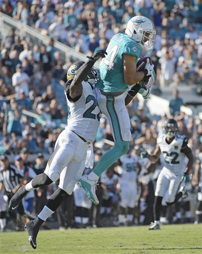 Miami Dolphins tight end Jordan Cameron makes the catch against Jacksonville Jaguars James Sample  during the first half of an NFL football game Sunday Sept. 20 2015 in Jacksonville Fla