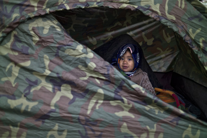 Afghan refugee Asma Mohammed 2 looks out a tent where she and her family spent the night at a collection point in the truck parking lot of the former border station on the Austrian side of the Hungarian Austrian border near Nickelsdorf Austria Friday