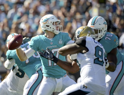 Miami Dolphins quarterback Ryan Tannehill throws a pass as he is pressured by Jacksonville Jaguars defensive end Chris Clemons left during the first half of an NFL football game in Jacksonville Fla. Injurie