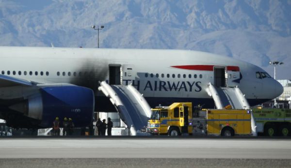 Firefighters stand by a plane that caught fire