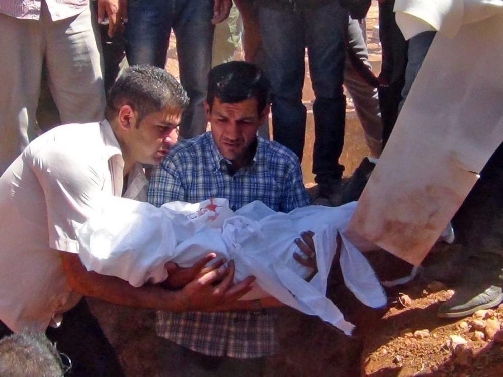 Abdullah Kurdi holds the body of his 3-year-old son Aylan Kurdi during the burial of the boy his brother Friday and his mother at a funeral in Kobane Syria