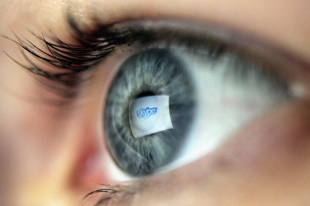 Logo of the internet communications company Skype is reflected in the eye of a woman