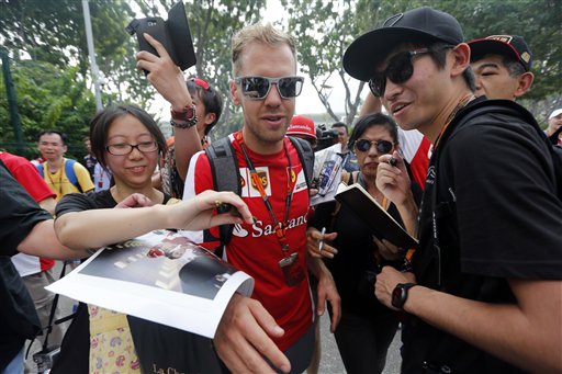 Ferrari driver Sebastian Vettel of Germany tries to get past fans as he arrives at the paddock ahead of the third practice session at the Singapore Formula One Grand Prix on the Marina Bay City Circuit in Singapore Saturday Sept. 19 2015.(AP