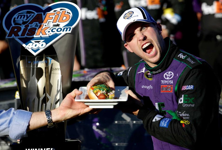 Denny Hamlin prepares to eat a Chicago style hot dog in Victory Lane after winning the NASCAR Sprint Cup Series auto race at Chicagoland Speedway Sunday Sept. 20 2015 in Joliet Ill