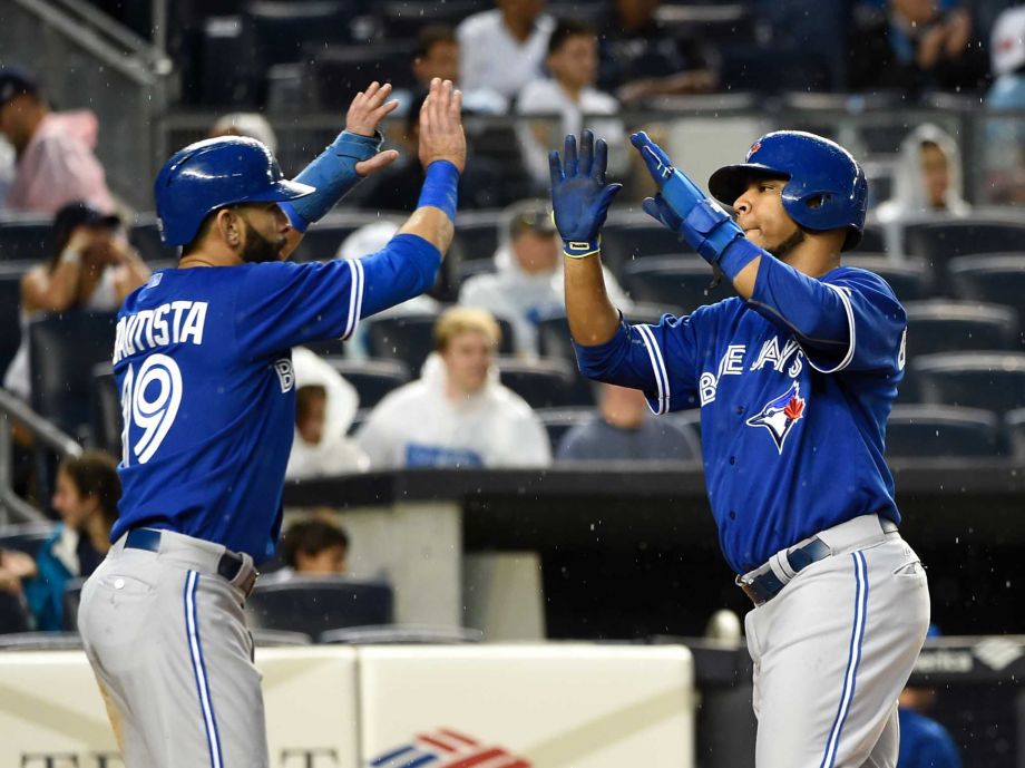 Toronto Blue Jays Jose Bautista and Edwin Encarnacion high five at home plate after scoring on Russell Martin's double off of New York Yankees starting pitcher Ivan Nova in the second inning in Game 2 of a doubleheader baseball game at Yankee Stadi