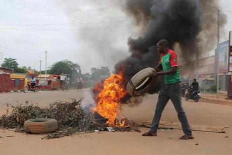 A protester threw a tire on a roadblock in Burkina Faso on Friday. The military seized power there this week in a coup