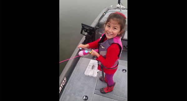 Dad encourages daughter as she catches a huge bass with her Barbie fishing rod