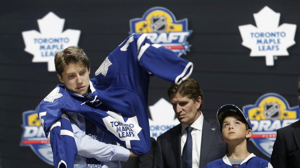 Mitch Marner puts on a Toronto Maple Leafs sweater after being chosen fourth overall during the first round of the NHL hockey draft Friday