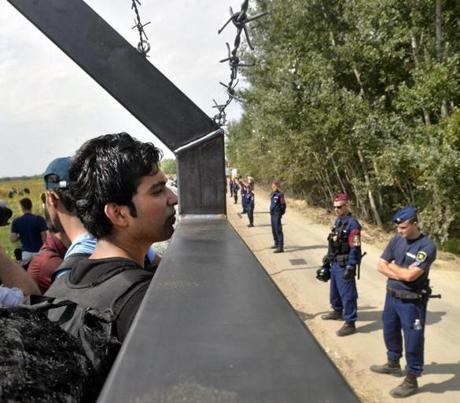 Migrants looked through a fence between Serbia and Hungary near Horgos Serbia on Tuesday. Hungary has declared a state of emergency in two of its southern counties because of the migration crisis giving special powers to police and other authorities