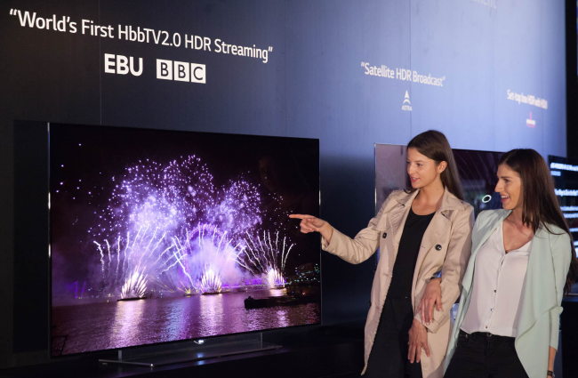 Models pose with LG Electronics’ OLED TV compatible with the HDR technology which enhances the level of brightness and darkness