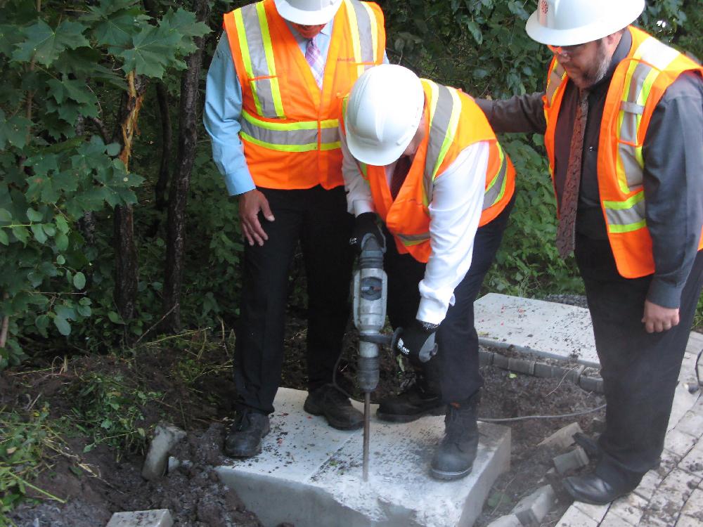 Montreal Mayor Denis Coderre centre uses a jackhammer to destroy a concrete foundation laid for an unauthorized community mailbox at the entrance to Anse-a-l'Orme Nature Park in Montreal on Thursday