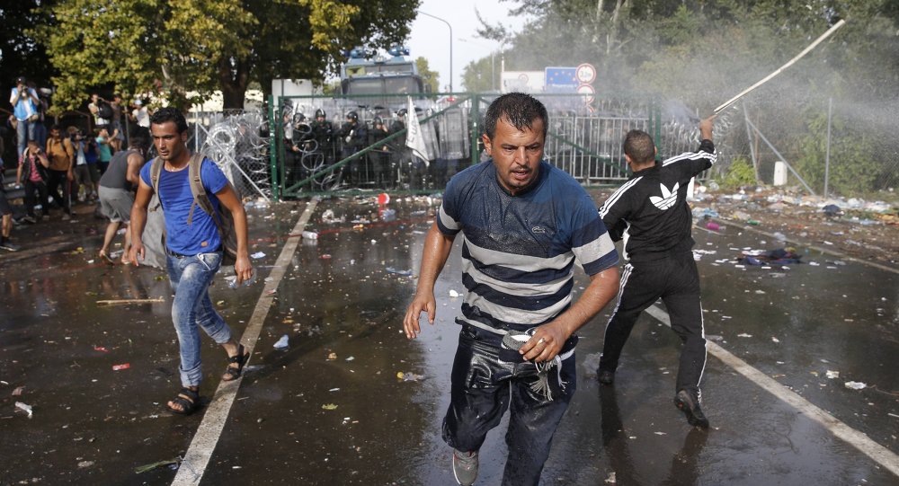 Migrants run as Hungarian riot police fires tear gas and water cannon at the border crossing with Serbia in Roszke Hungary