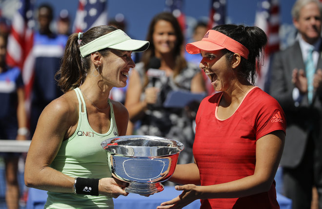 Martina Hingis of Switzerland left and Sania Mirza of India celebrate with the championship trophy after defeating Casey Dellacqua of Australia and Yaroslava Shvedova of Kazakhstan in the women's doubles championship match of the U.S. Open tennis