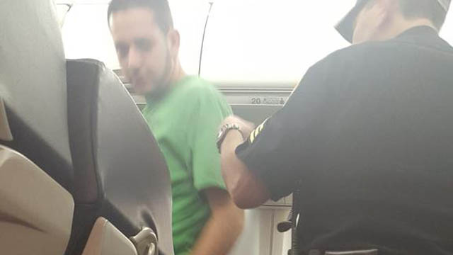 A police officer detains one of six passengers who became unruly on a Southwest Airlines flight from San Diego to Chicago prompting the pilot to divert the plane to Amarillo Texas