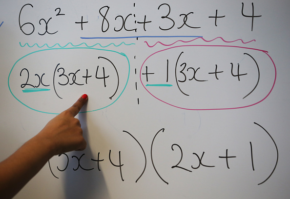 LONDON ENGLAND- DECEMBER 01 A teacher writes an equation on a whiteboard during a maths lesson at a secondary school