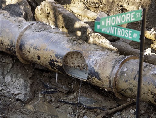 36 inch water main break that crumbled pavement sending thousands of gallons of water onto a major city street turning it into what looked like a small lake rests uncovered as construction crews attempt to rep