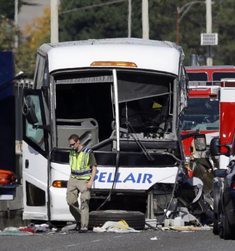 An emergency worker walks in front of a charter bus that was involved in a fatal crash with a'Ride the Ducks amphibious tour bus Thursday Sept. 24 2015 in Seattle