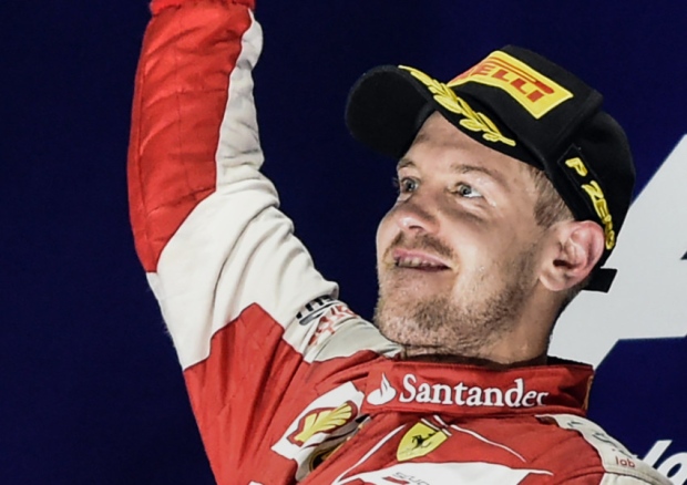 Sebastian Vettel stands aloft the podium to celebrate his victory