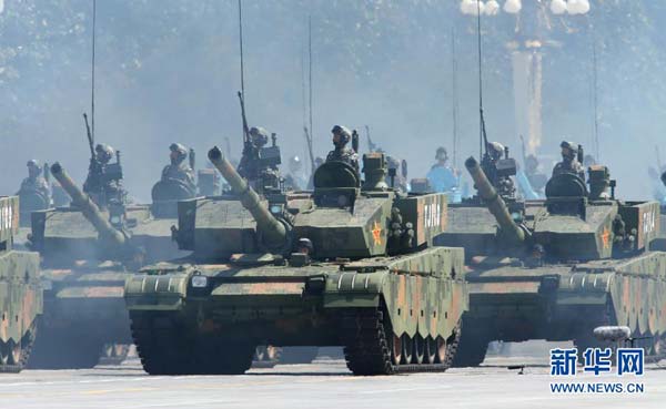 Soldiers of China's People's Liberation Army hold guns while standing in armored vehicles during the military parade