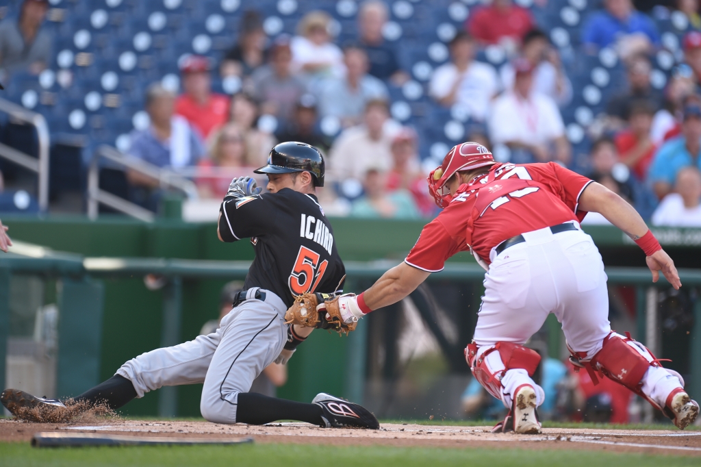 Ichiro Suzuki #51 of the Miami Marlins beats the tag by Wilson Ramos #40 of the Washington Nationals on a Christain Yelch #21 single in the first inning during a baseball game at Nationals Park