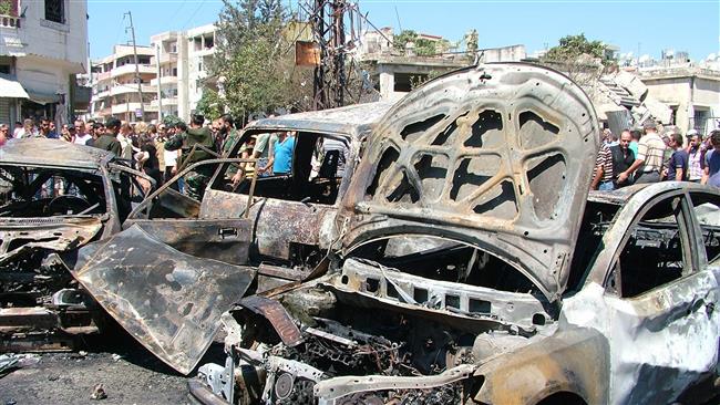 People look at the wreckage of vehicles at the site of a reported car bombing in the government-controlled coastal city of Latakia