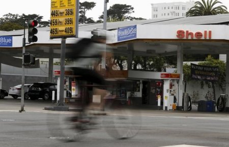 A cyclist rides past a sign showing the prices of gas at a filling station in San Francisco California