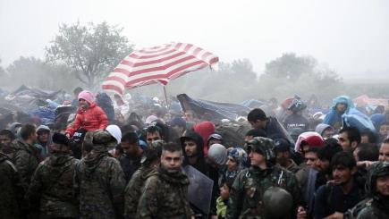 Refugees and migrants wait to pass from the northern Greek village of Idomeni to southern Macedonia