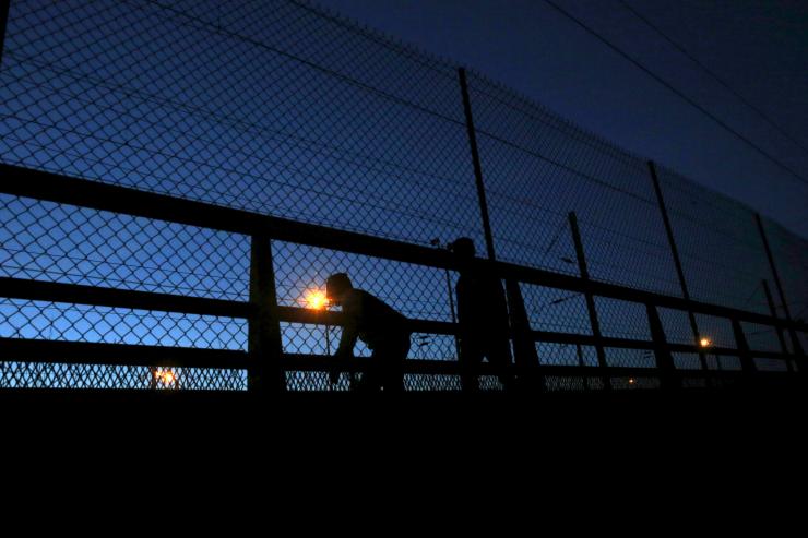 Two refugees walk after crossing the fence as they attempt to access the Channel Tunnel in Frethun near Calais France Aug. 8 2015.                    Reuters