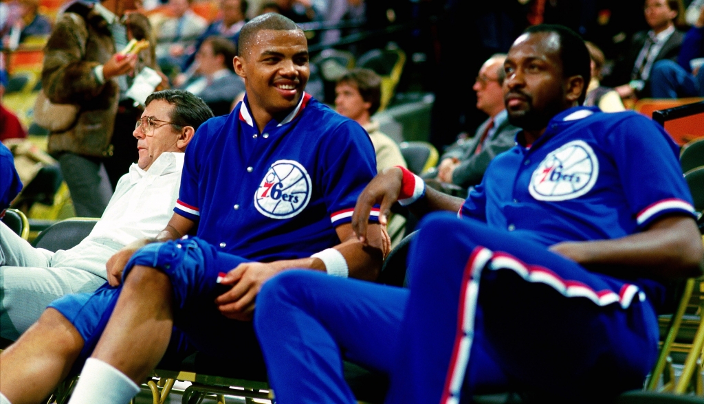 PHILADELPHIA- 1985 Charles Barkley #34 of the Philadelphia 76ers shares a light moment with teammate Moses Malone #2 while resting on the bench during an NBA game in 1985 at The Spectrum in Philadelphia Pennsylvania