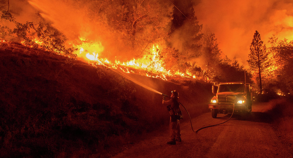 A firefighter douses flames from a backfire while battling the Butte fire near San Andreas California