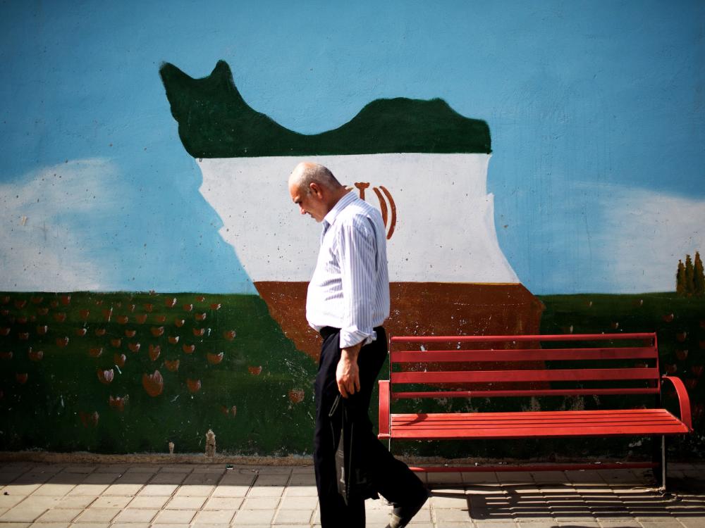 An Iranian man walks past a mural displaying an outline of Iran adorned in the colors of the country's national flag on June 29 in Tehran. A large majority of Iranians appears to support the nuclear deal