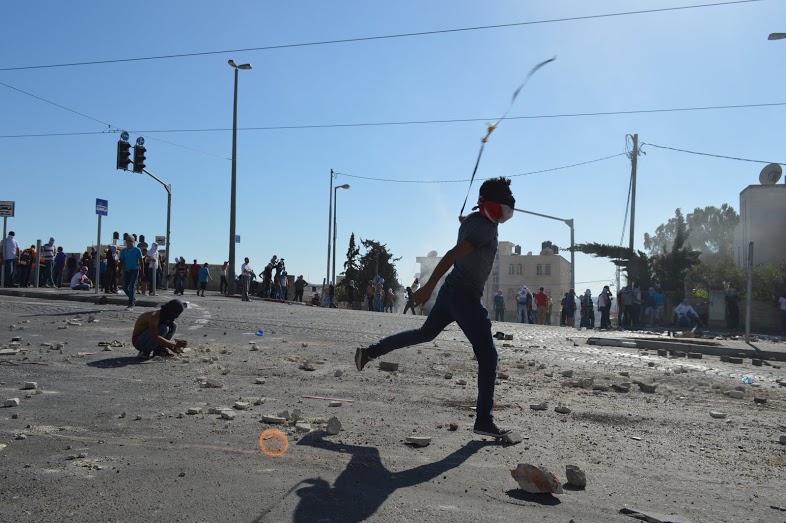 Young man from Shufat launches stones towards IDF with a catapult while other residents keep out of army fire