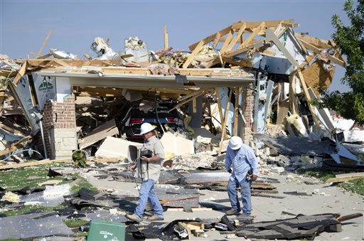 Workers walk around a house that exploded on Monday Sept. 21 2015 in Waxahachie Texas. A couple people were airlifted to a hospital after the explosion