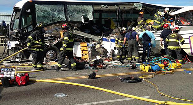 Firefighters assist victims after a crash between a bus and a tour vehicle on the Aurora Bridge in this