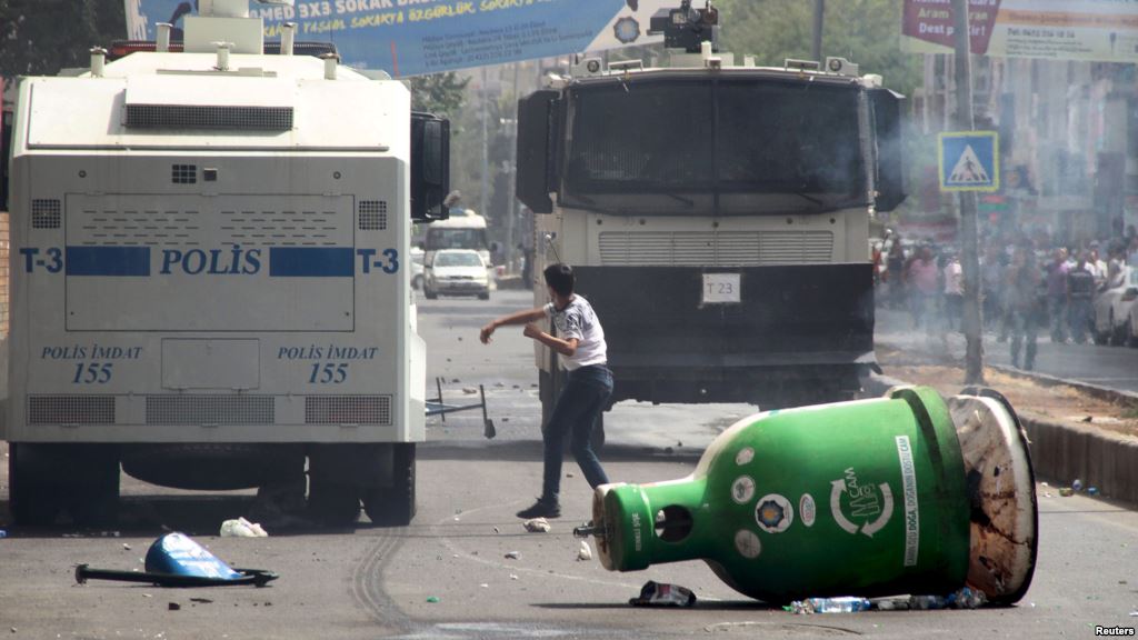 A protester throws stones at police vehicles in the Kurdish dominated southeastern city of Diyarbakir Turkey