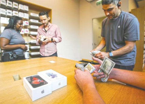 A customer pays cash for his Apple iPhone 6s and iPhone 6s Plus smartphones at the Apple store at The Grove in Los Angeles. — AP