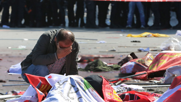 A man cries over the body of a victim at the site of an explosion in Ankara Turkey. Image AP