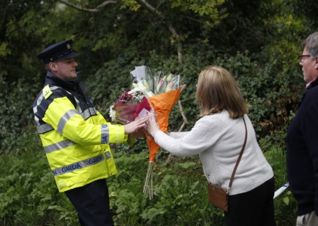 A woman arrives to leave flowers close to the scene of a fire in Carrickmines Dublin Ireland Saturday Oct. 10 2015