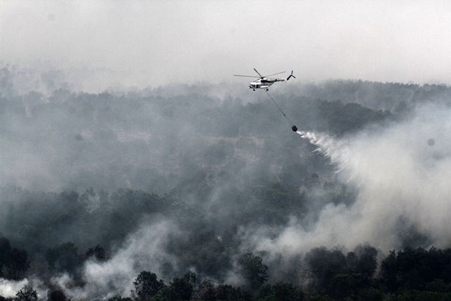 An Indonesian national board for disaster management MI-17 helicopter water-bombs a fire spot over Ogan Komering Ilir area in South Sumatra province